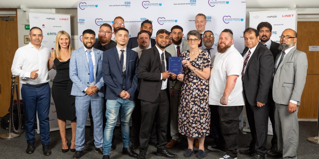 Chris Boseley and the Carlisle Support Services security team are all smiles with their Mitie Unsung Heroes Award, against a white backdrop with sponsors logos.