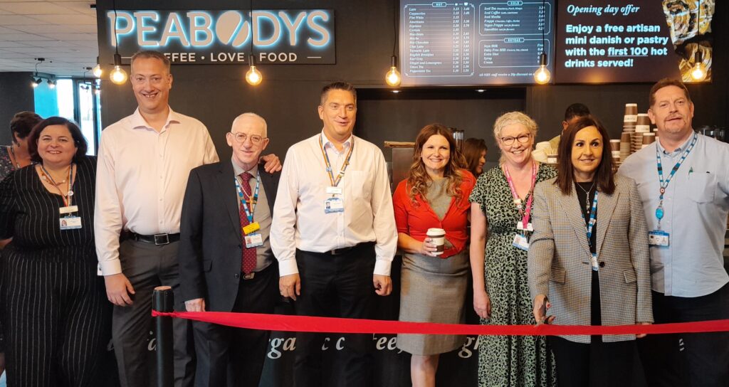 Several people standing in front of the new Peabodys Coffee outlet. There is a red ribbon in front of them, which is about to be cut to unveil the new shop.