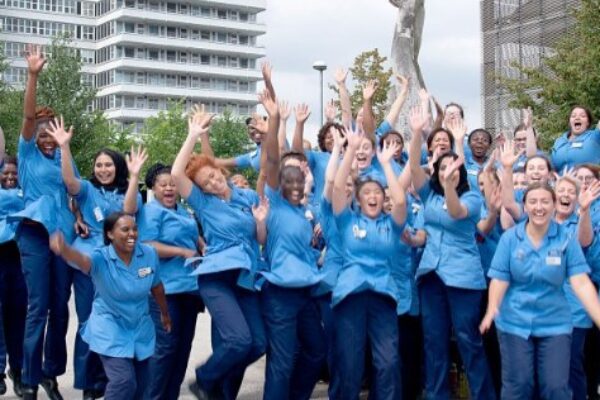 This photo features a large group of our student nurses in the Lister plaza, all throwing their hands in the air