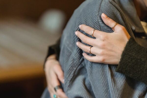 A person in grey clothing is held in a comforting embrace by another person