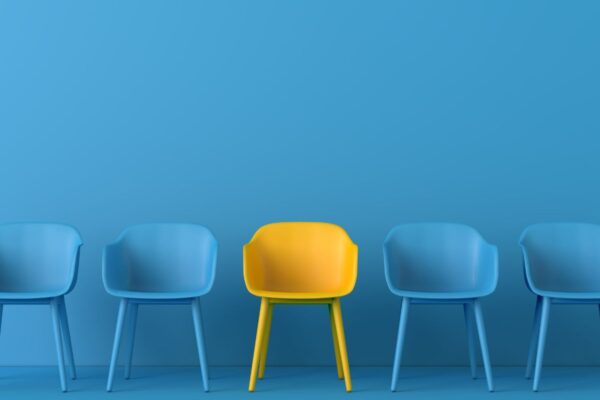 Row of blue chairs against a blue background, with one yellow chair in the middle of the row.