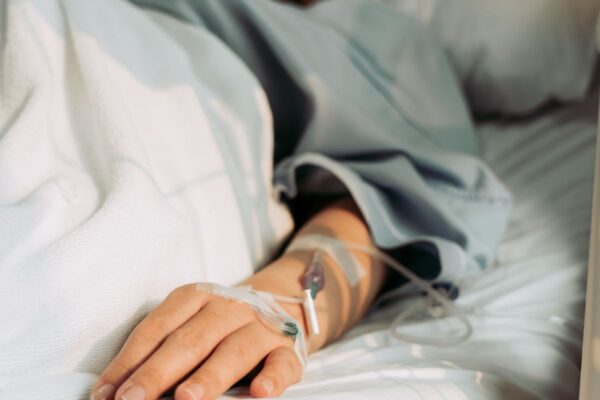 Close up of a patient in bed's arm, with a cannula.