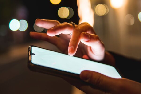 Person holding a mobile phone in one hand and typing on it with the other.