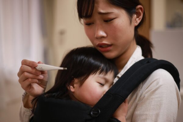 White asian mother looking worryingly at thermometer