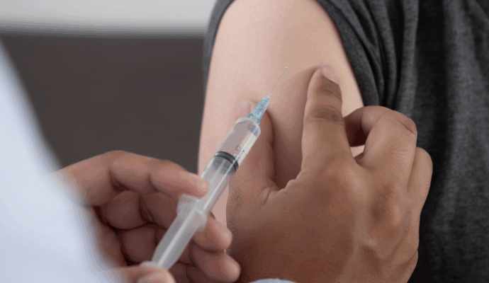 A black doctor giving a white patient the vaccine.