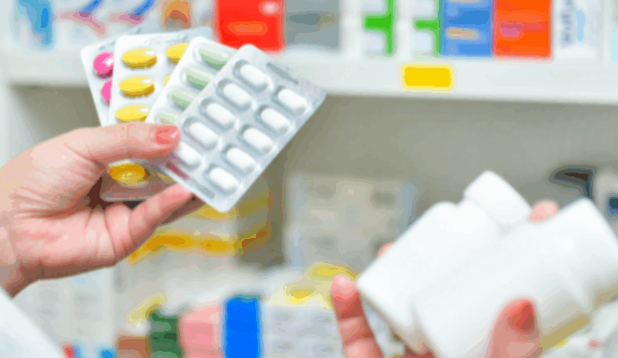 A pharmacist holding a variety of prescription medications.