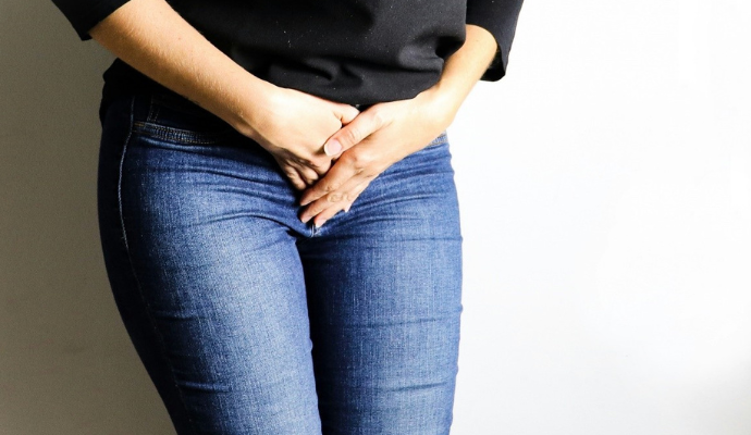 A woman experiencing pain in her groin is photographed clenching her hand over the pain site.