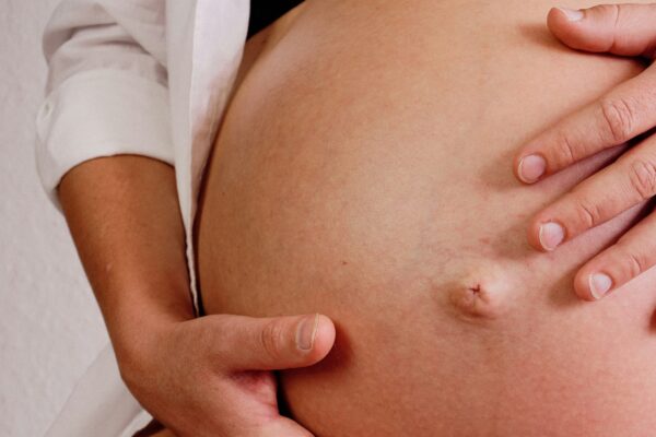 Royalty-free image of a pregnant women's bump. She is cradling it with both hands.