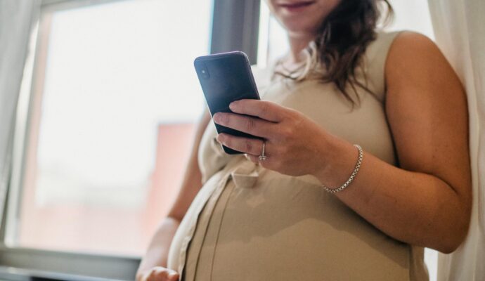 An image of a pregnant women looking at a mobile phone.